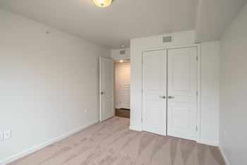 A room with white walls and a carpeted floor with two white doors.